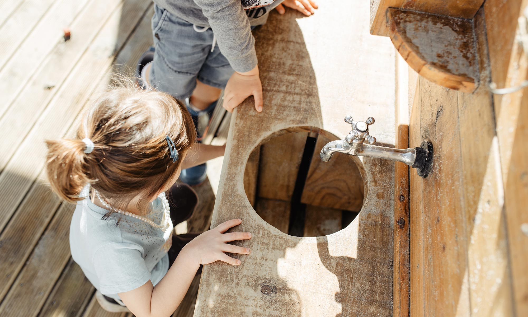 Children exploring a wooden water play structure together