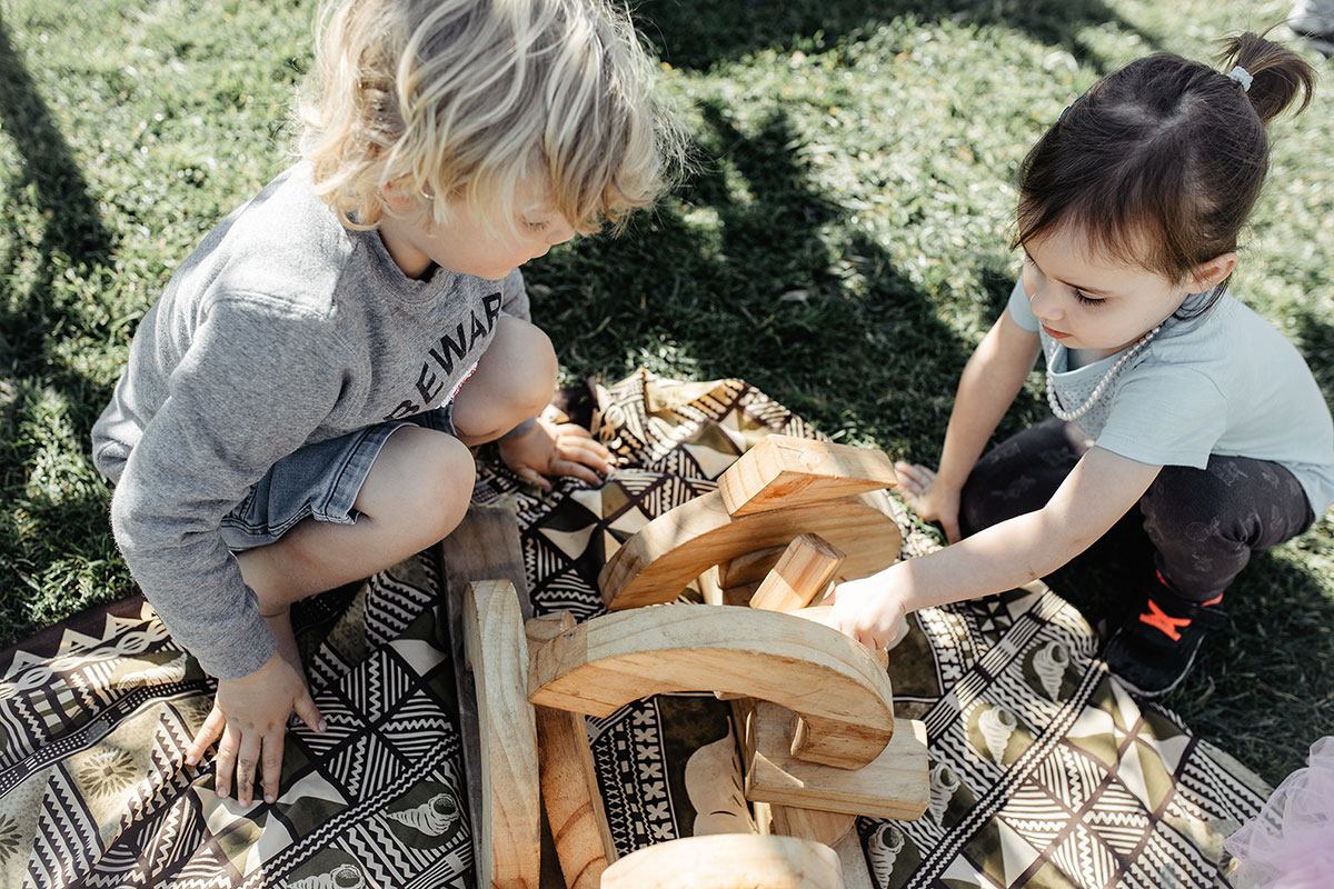 Two children building together with wooden blocks